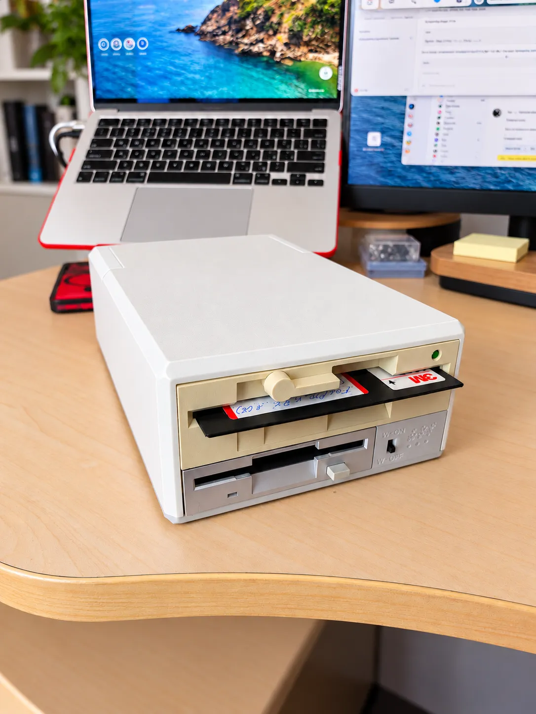Старые дисководы с дискетой стоят на столе рядом с современным Mac